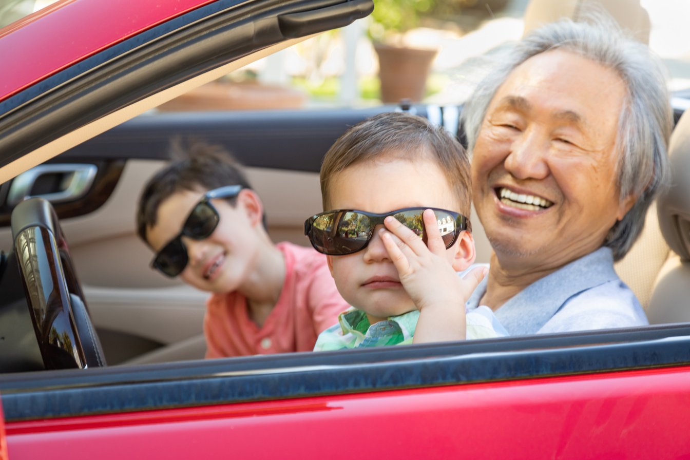 Chinese Granfather and Mixed Race Children Playing in Parked Car